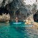 A woman standing on a paddleboard near a coastal cave